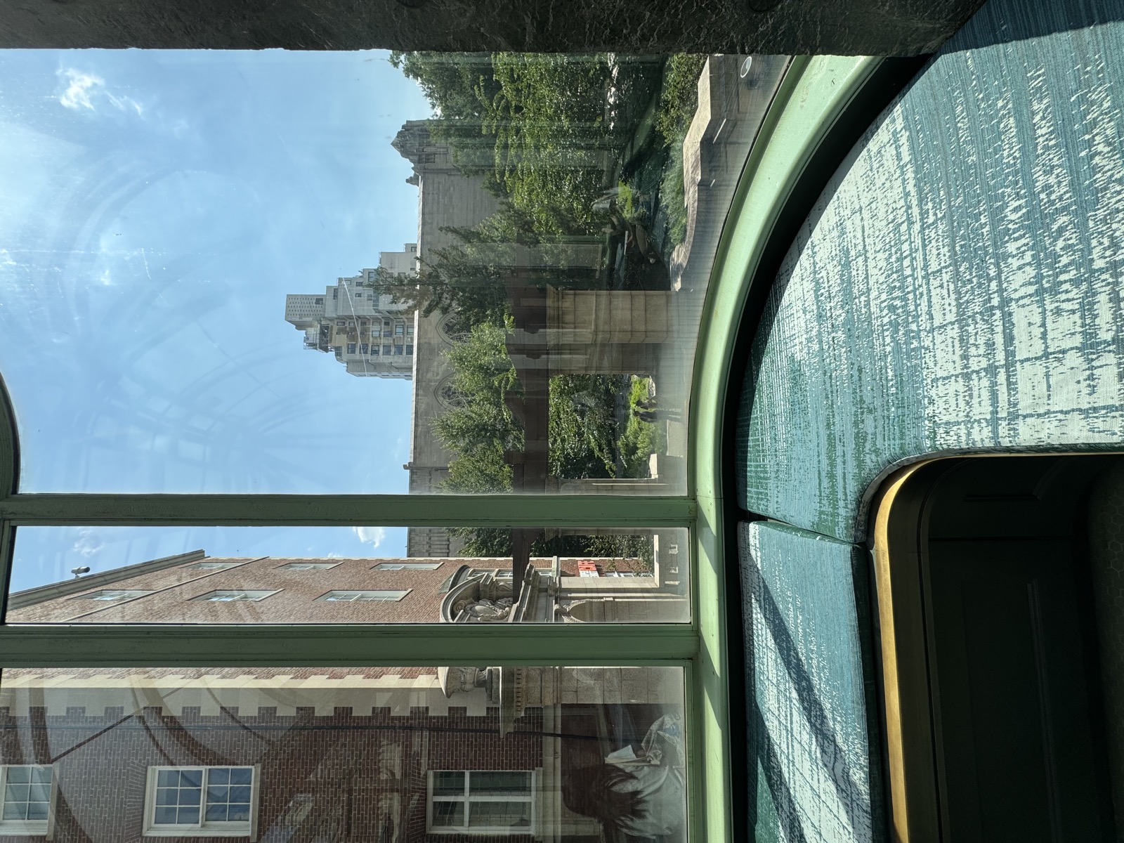 View through an arched window toward a stone building and trees