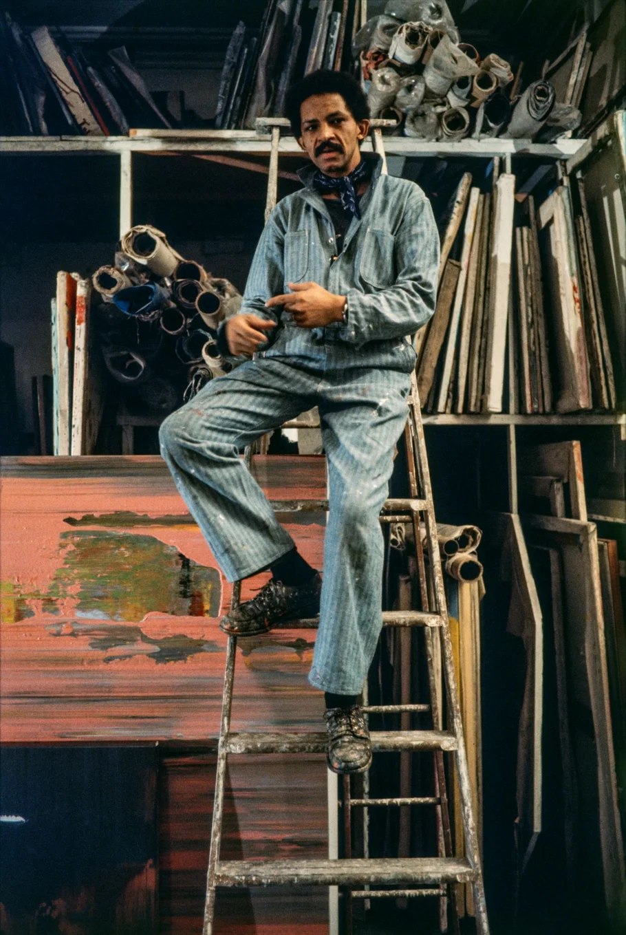 Portrait of Jack Whitten standing on a ladder in his studio