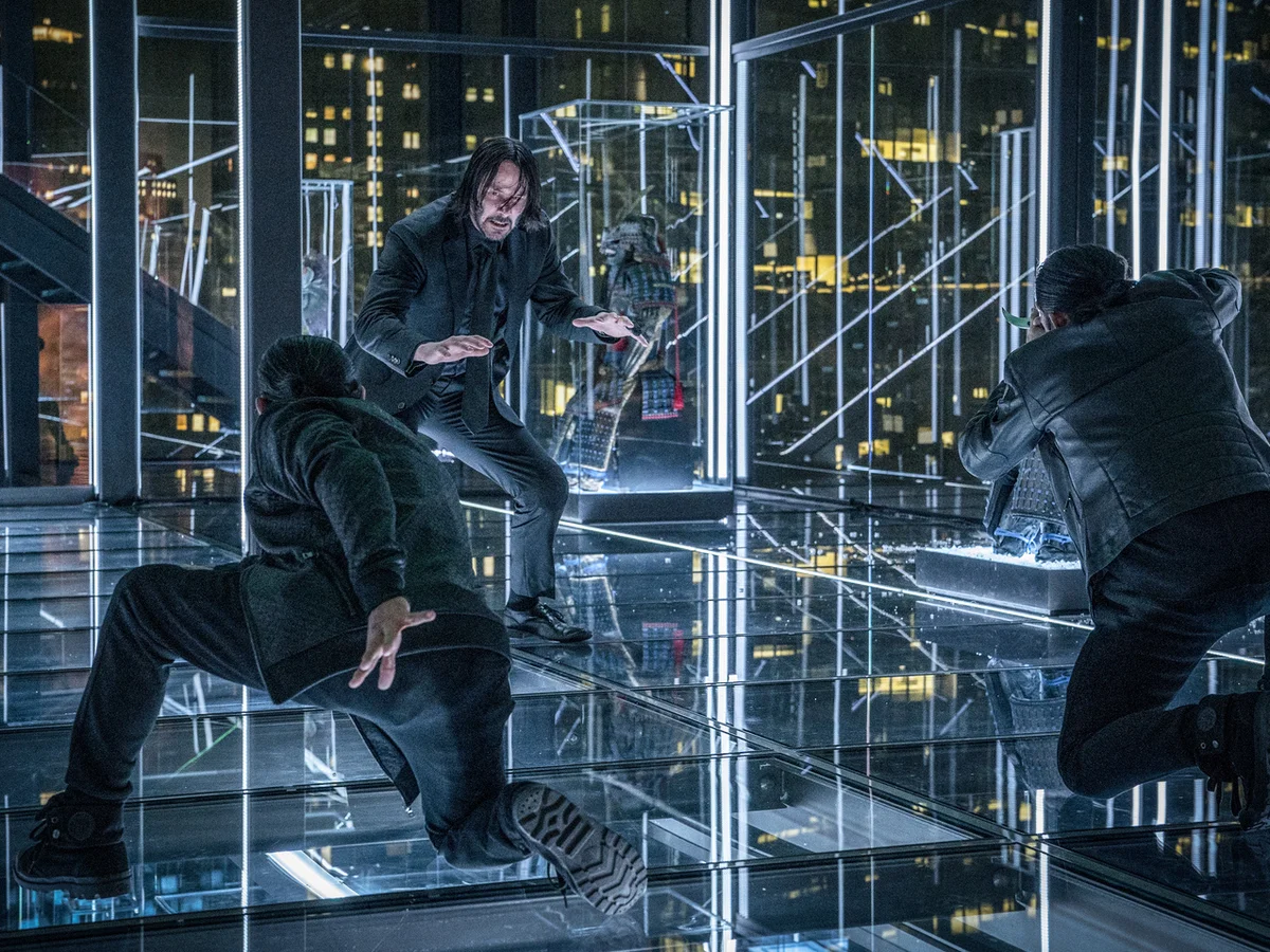 John Wick fighting two opponents in a glass-walled room in John Wick 3